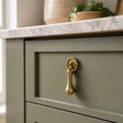 Solid brass tear drop handle on a sage green Shaker kitchen drawer