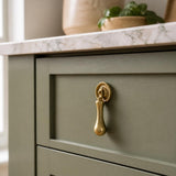 Solid brass tear drop handle on a sage green Shaker kitchen drawer