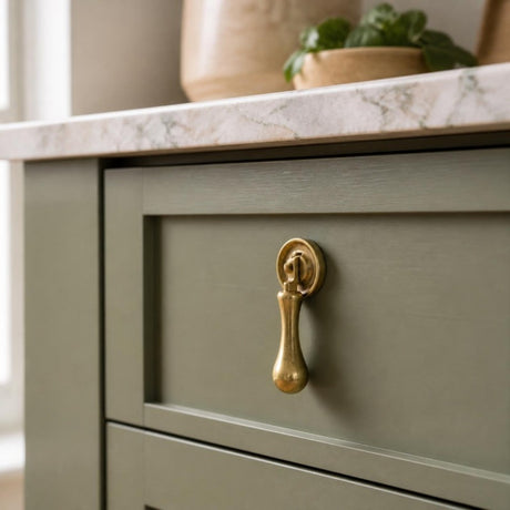 Solid brass tear drop handle on a sage green Shaker kitchen drawer