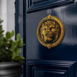 Brass lion head door knocker on a navy blue front door