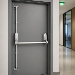 Emergency exit push bar with vertical bolts on a grey fire exit door