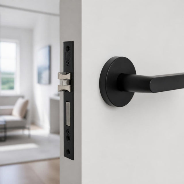 Matt black cylinder mortise lock fitted in the edge of a white door