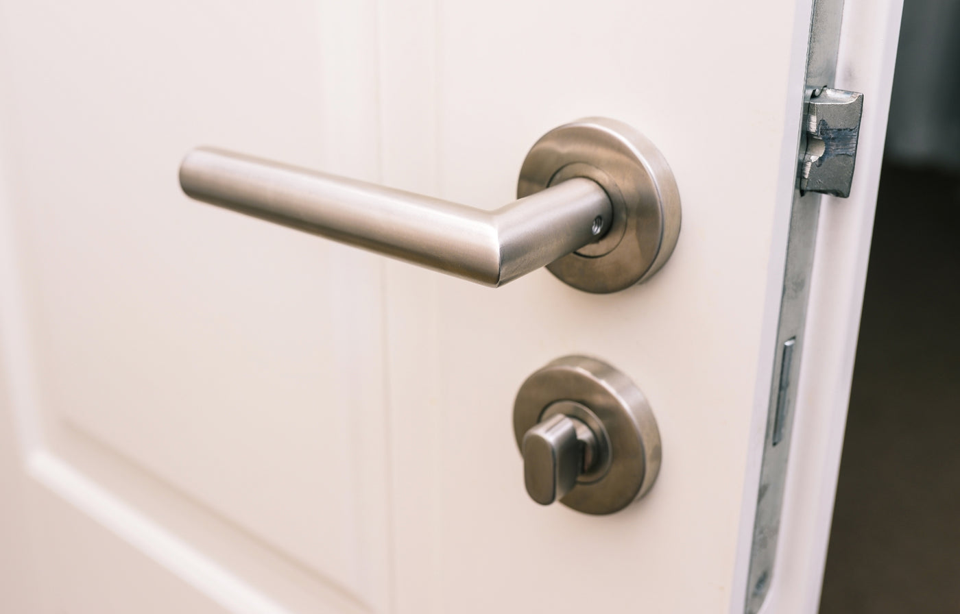 brushed_stainless_steel_door_handle_on_round_rose_with_thumbturn_cylinder_on_white_panelled_door