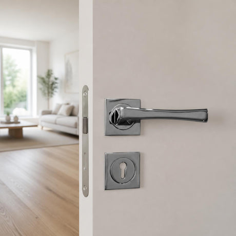 Italian polished chrome lever handle on square rose on a white timber door ajar to a living room